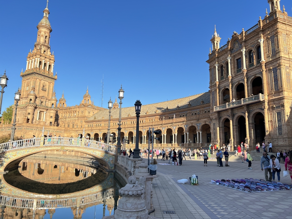 Plaza with historic buildings and people walking around.