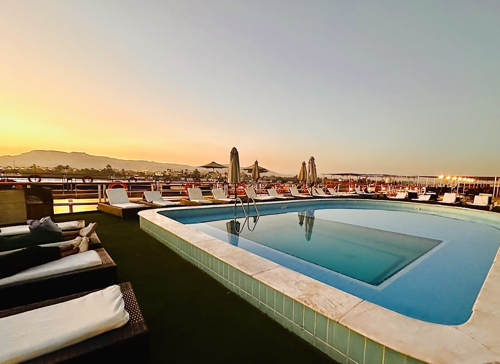 Pool on a cruise ship with mountains in the background.