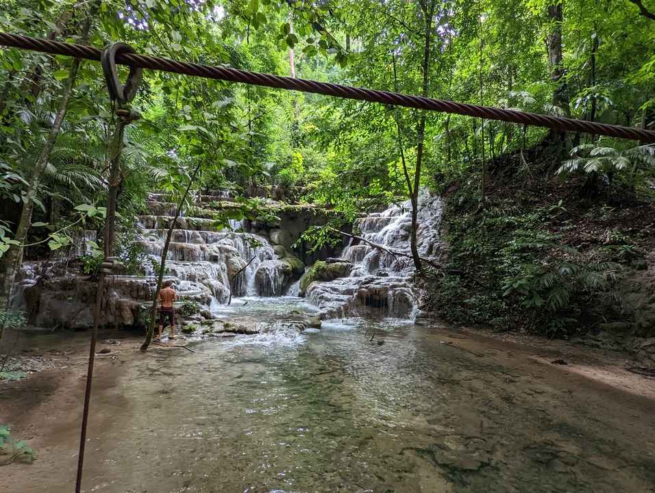 Waterfall cascading over rocks into a pool in a lush forest.