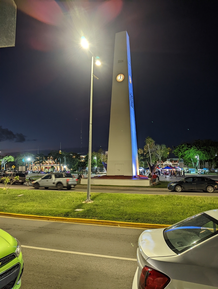 Illuminated monument at night with people in the foreground.
