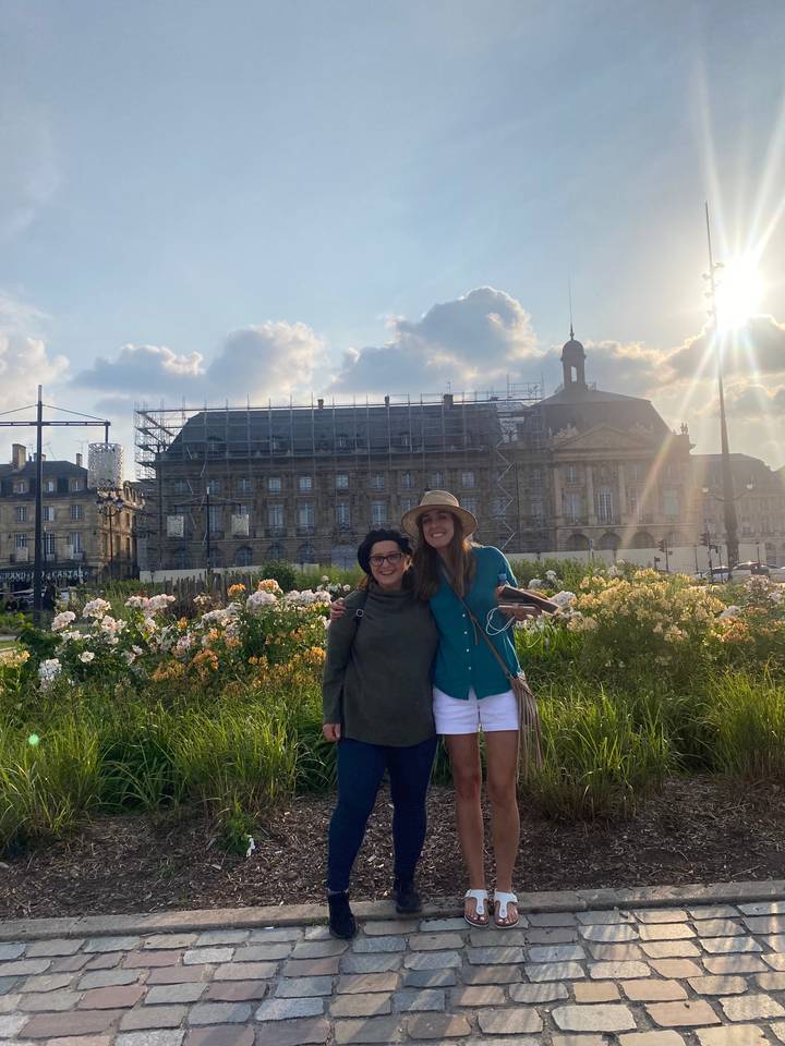 Two women posing in a garden with a historic building in the background.