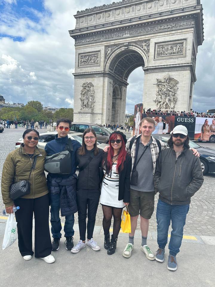 A group of people posing in front of the Arc de Triomphe.