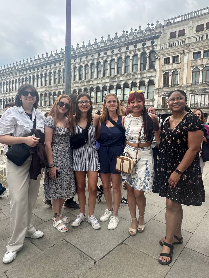 Group of people posing by a historical building.