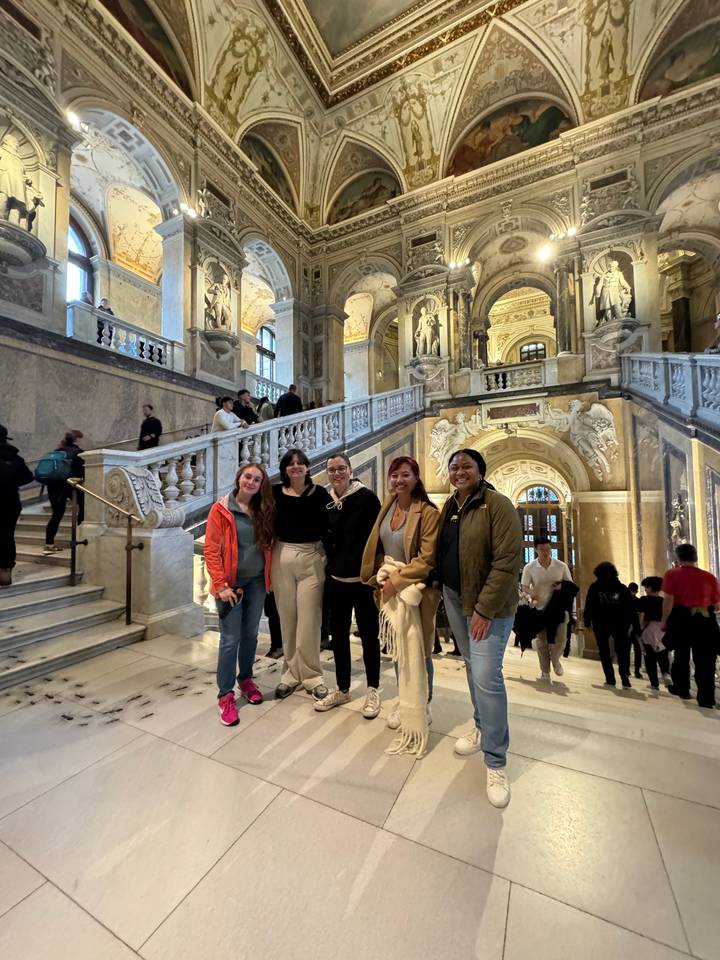People posing inside a grand hall with ornate interior decorations.