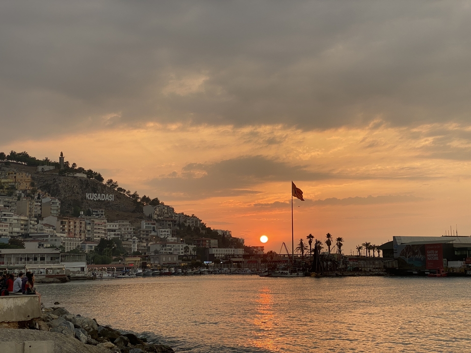 A coastal townscape at sunset with a Turkish flag.