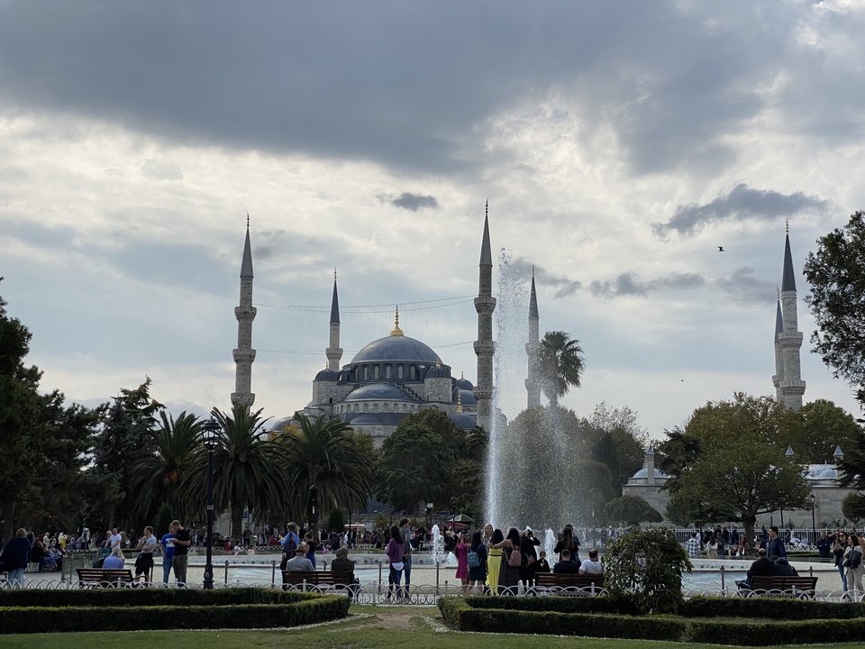 A famous mosque with fountains and crowds in the foreground.