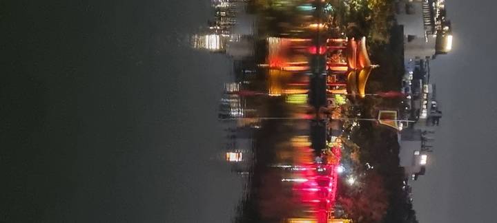 Colorful nighttime reflections on a body of water with city lights.
