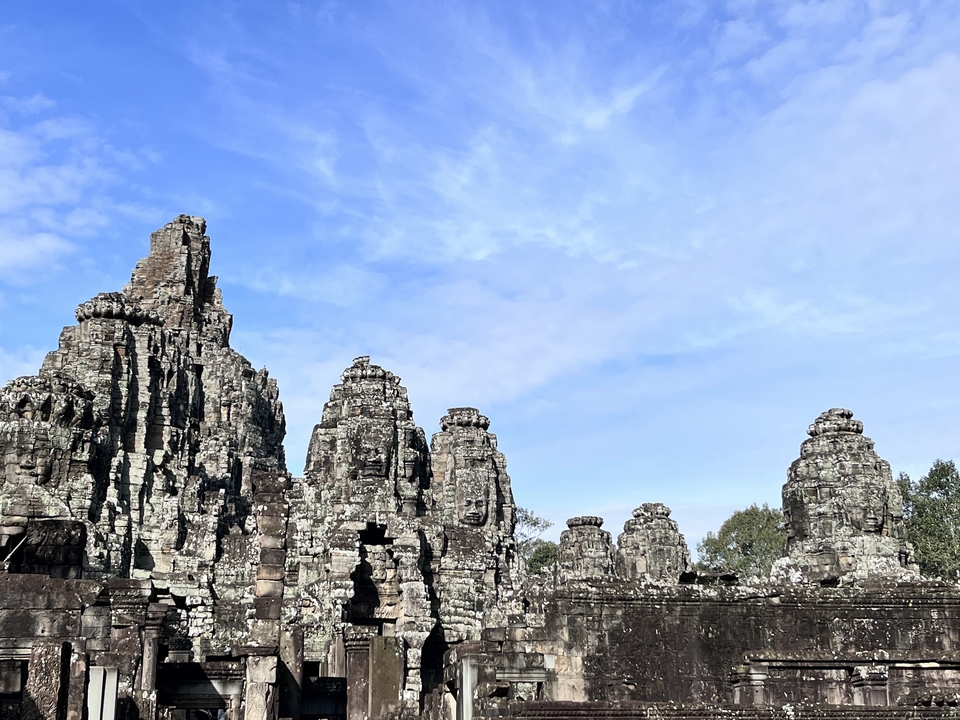 Face towers of Angkor Thom under a clear sky.