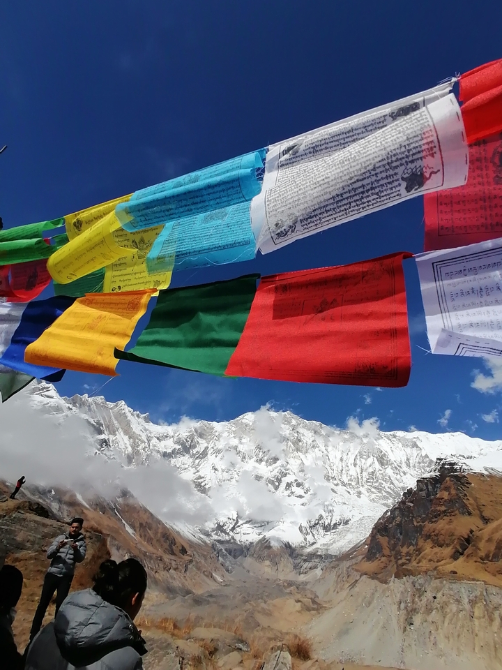 Drapeaux de prière colorés avec des montagnes enneigées en arrière-plan.