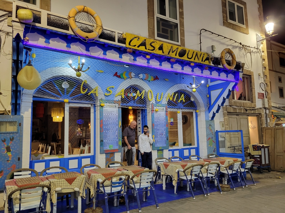 Front view of a decorated restaurant named Casa Mounia with two people standing outside.