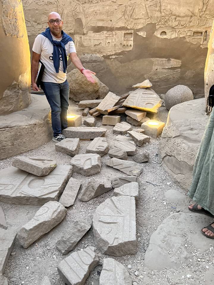 A person posing next to an exhibit of ancient carvings and artifacts.