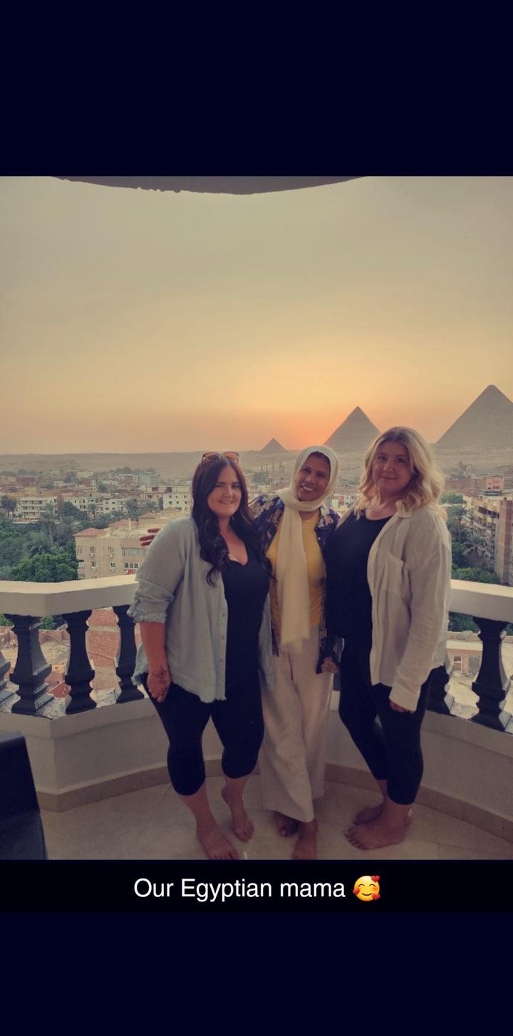 Three women posing with pyramids in the background.