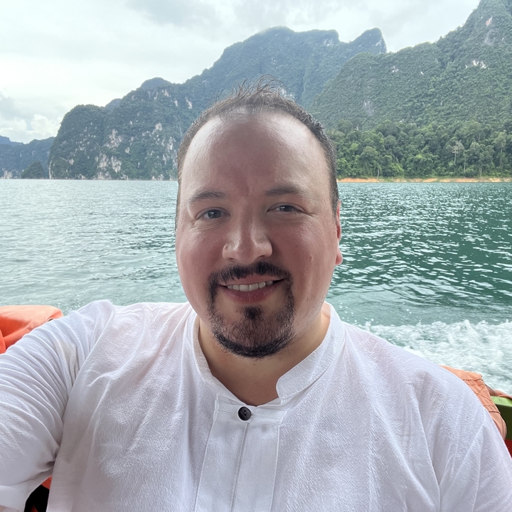 Person in a boat on a lake with mountains in the background.