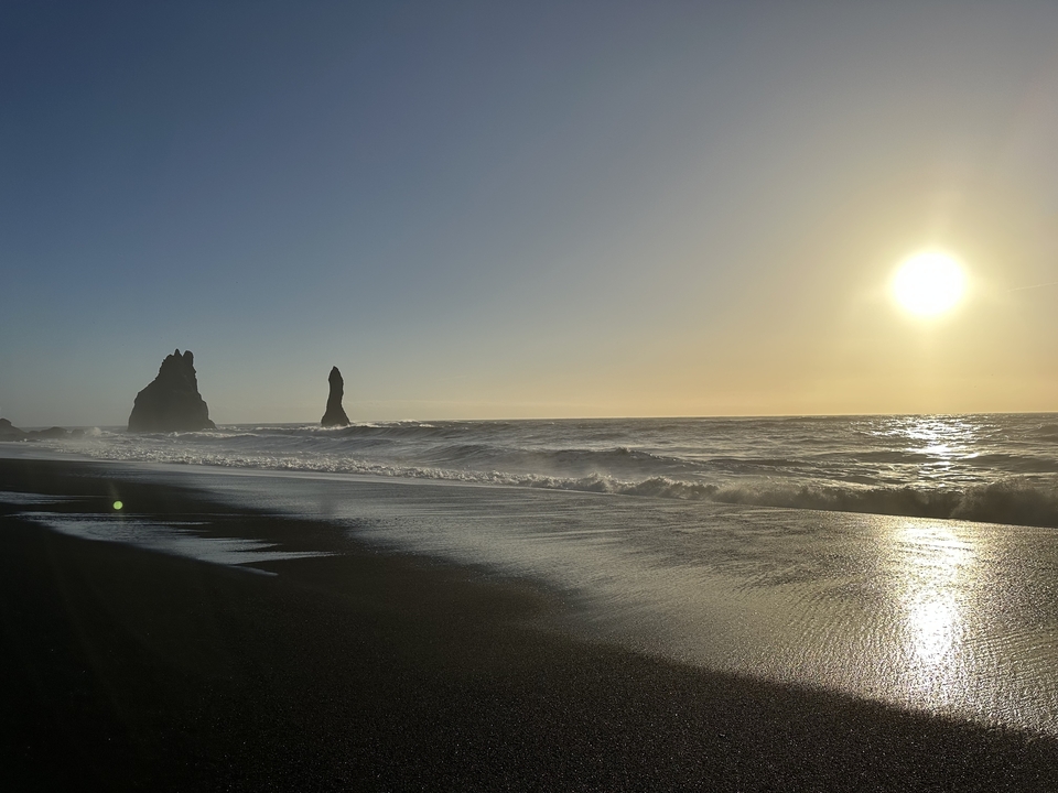 Black sand beach with sea stacks at sunrise.
