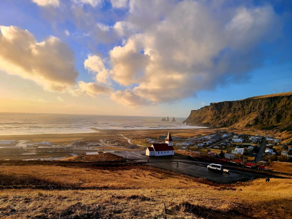 Scenic view of a coastal village with a church overlooking a sea in Iceland.