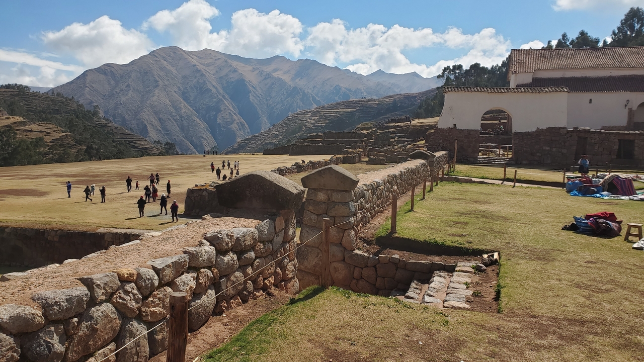 Visitors exploring the ruins with mountains in the background.