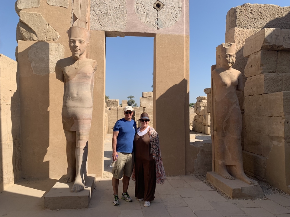 Two tourists posing in front of ancient Egyptian columns.