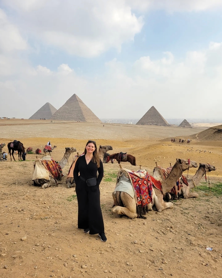Woman with camels and pyramids in the background