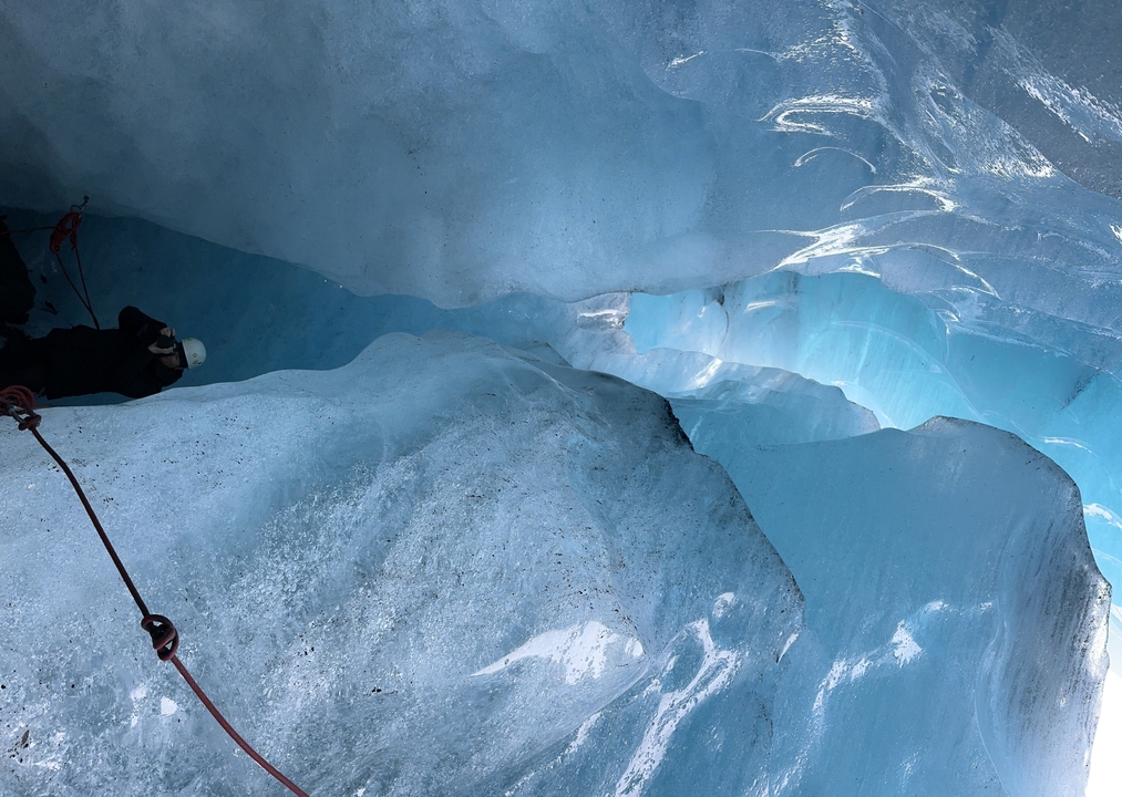 Ice cave with a person exploring inside.