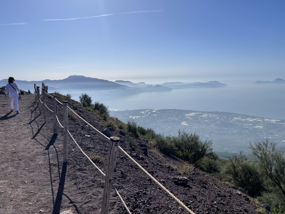 View from a mountain trail overlooking the Italian coastline with person walking.