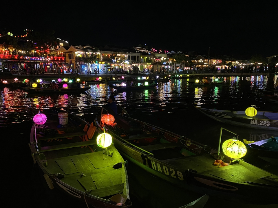 Colorful lanterns on boats in a busy river market at night.
