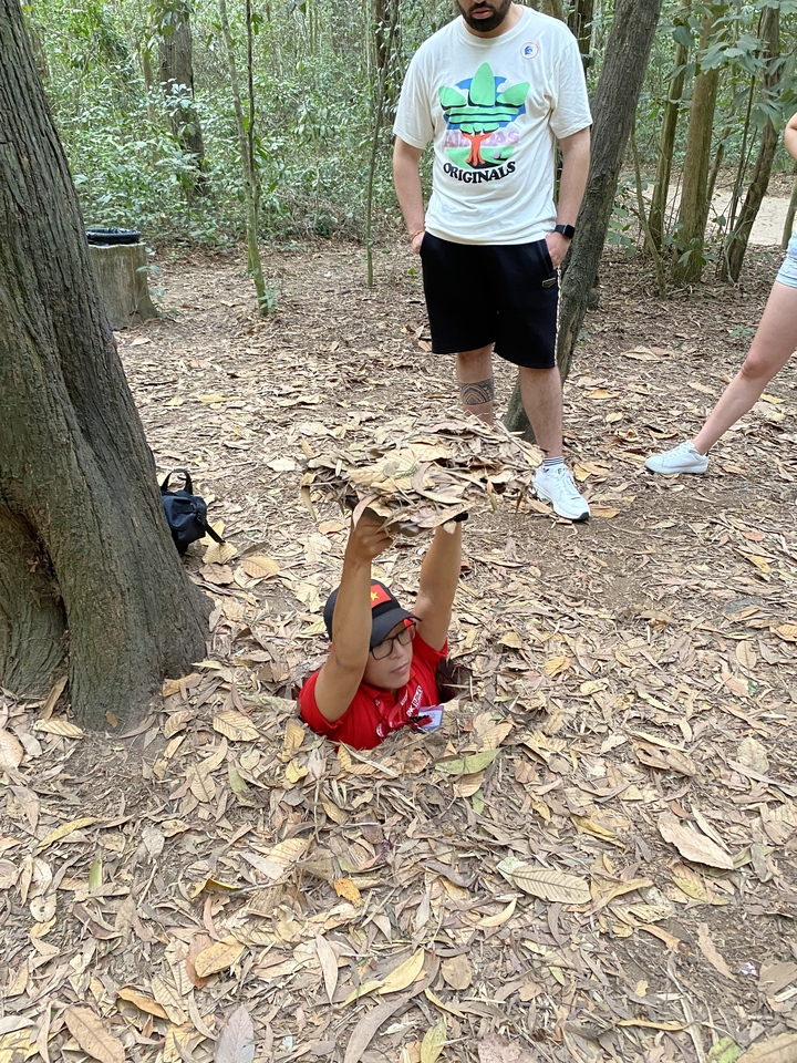 Person emerging from a tunnel covered with leaves.