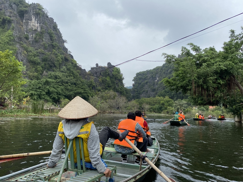 People in boats on a scenic river surrounded by rocky mountains.