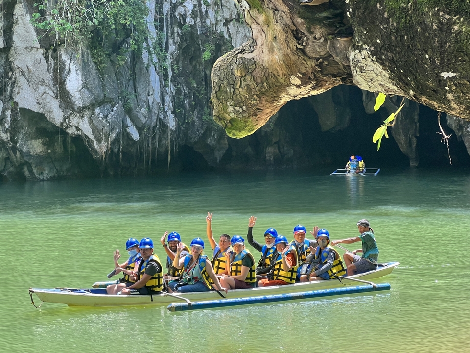 Group of people in a boat waving at the camera.