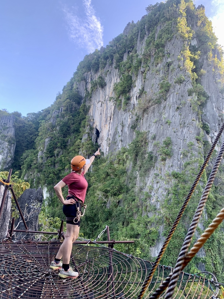 Person pointing upwards on a rugged cliff.