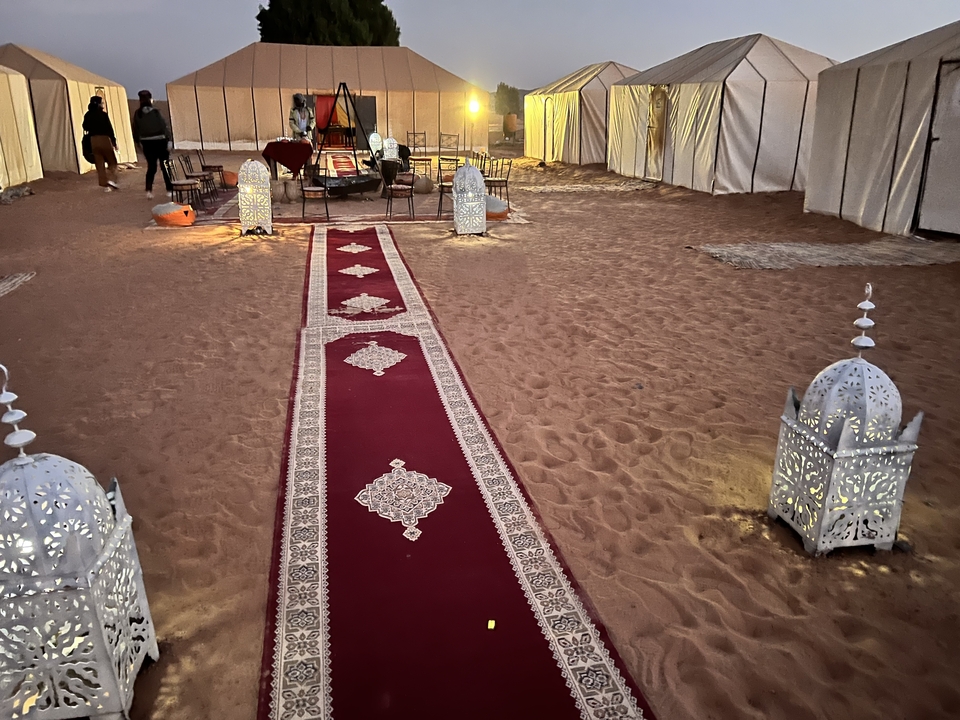 Lanterns and red carpet inside a desert camp.