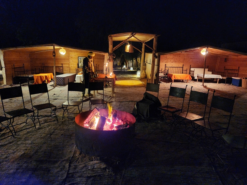 Cozy campfire setup with chairs and tables in a desert camp.