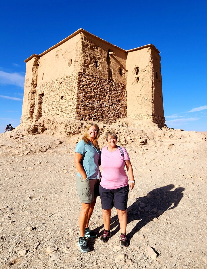 Two people in front of a historical desert structure.
