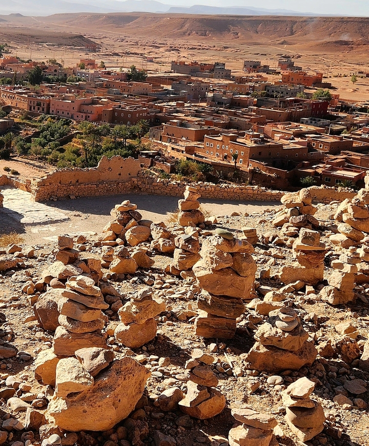 Stacked stones in front of a traditional desert village.