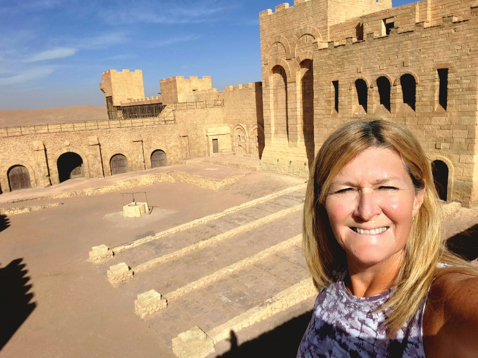 Person taking a selfie in front of a historical desert fortress.