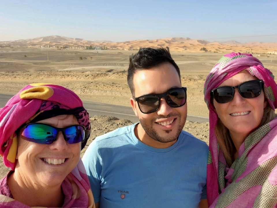 Three people wearing colorful clothing and sunglasses, in the desert.