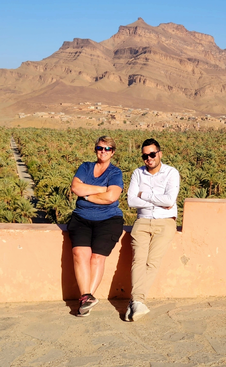 Two people sitting in front of a lush palm grove.