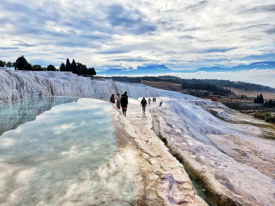 People walking along natural travertine terraces.