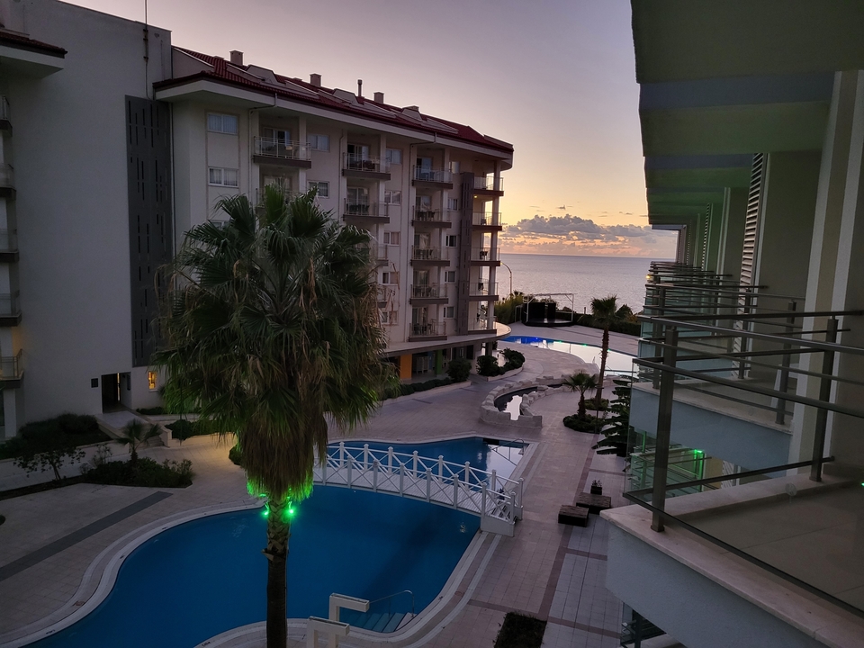 Hotel view with a pool and ocean in the distance.