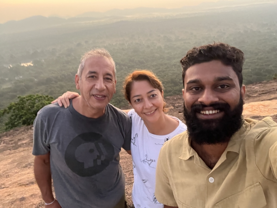 Three people smiling for a selfie with a forested background.