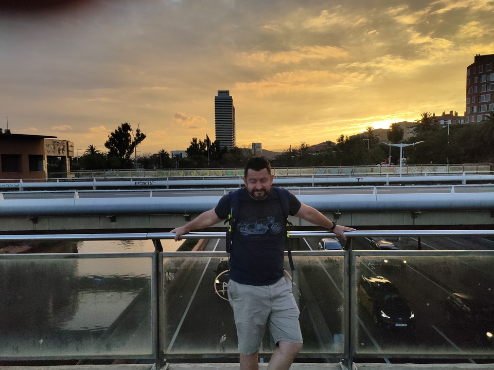 Personne posant sur un pont au coucher du soleil avec horizon urbain.