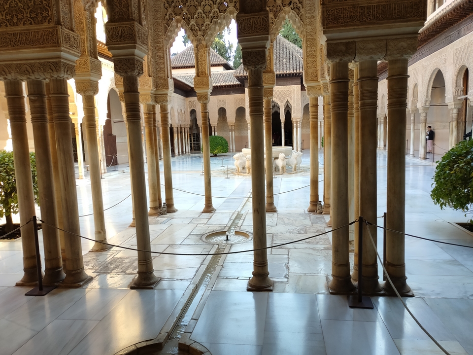 Palais avec des colonnes et une fontaine centrale.