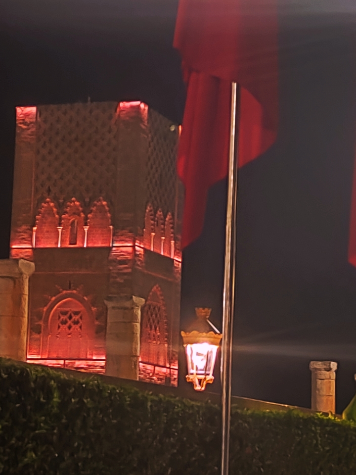 Structure ornée éclairée la nuit avec des drapeaux visibles.