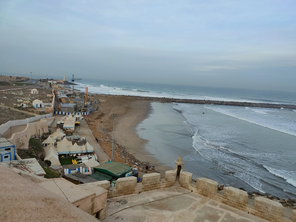 Vue côtière avec plage et petites structures.