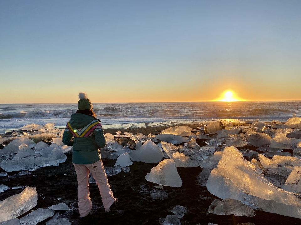 Personne debout sur une plage glacée au coucher du soleil.