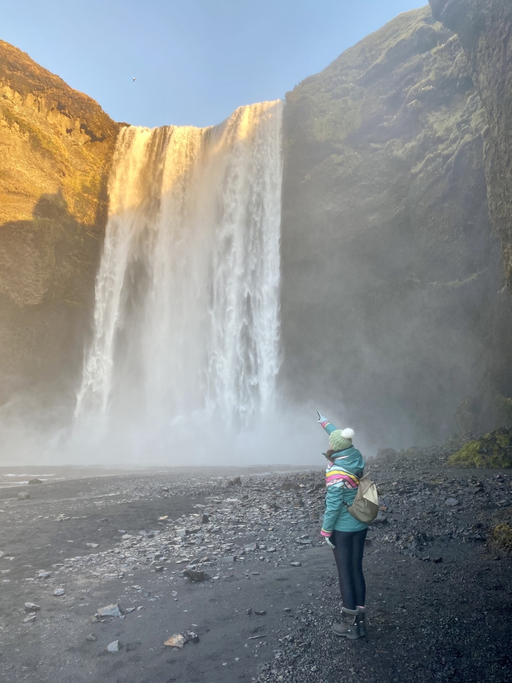 Personne pointant du doigt une grande cascade.