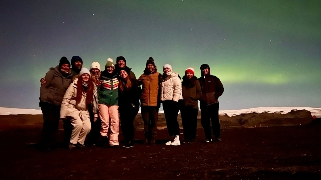 Groupe de personnes avec en arrière-plan les aurores boréales.