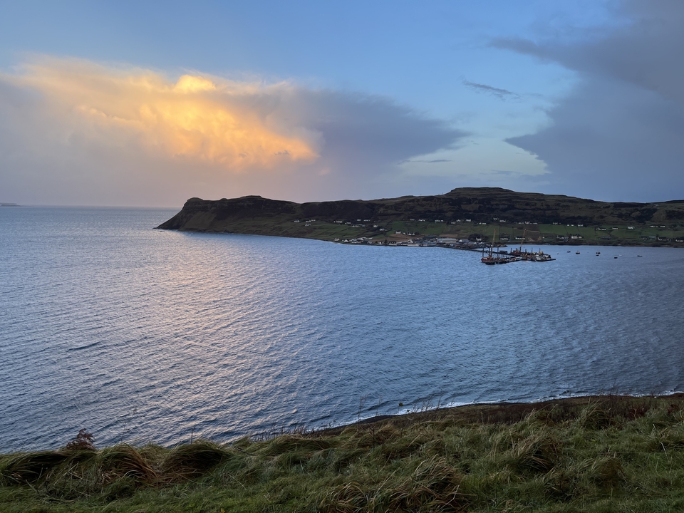 A scenic coastal landscape with a village and mountains.