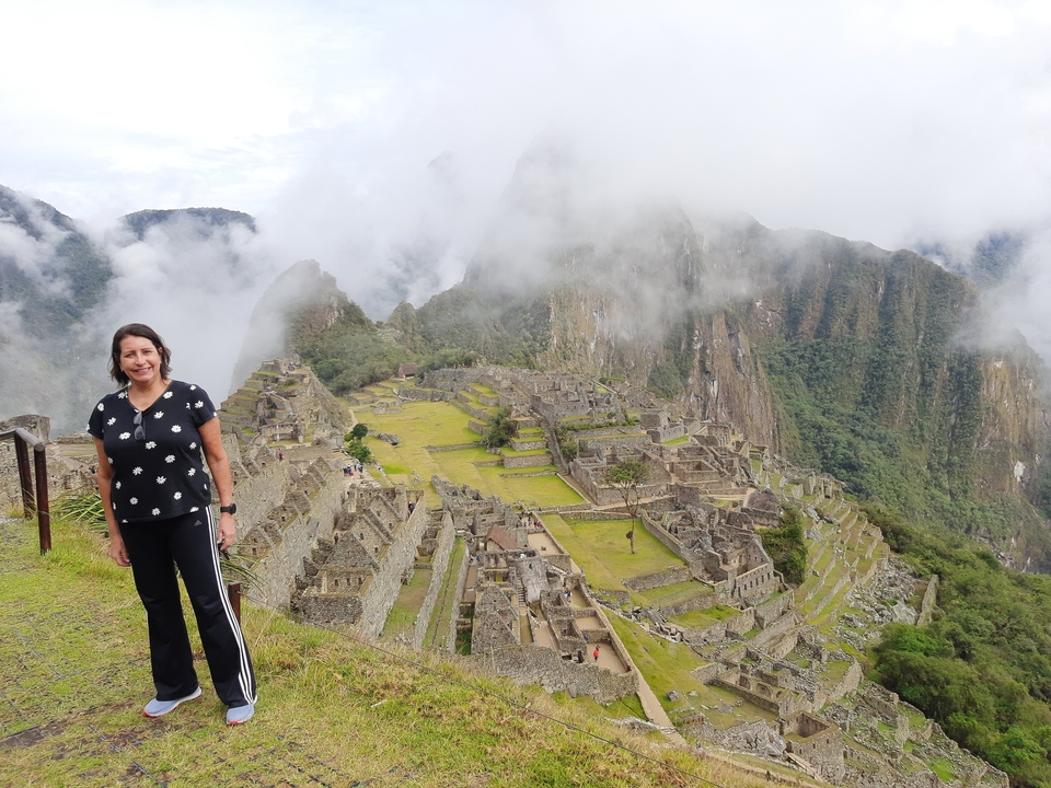 Woman with Machu Picchu ruins in the misty background.