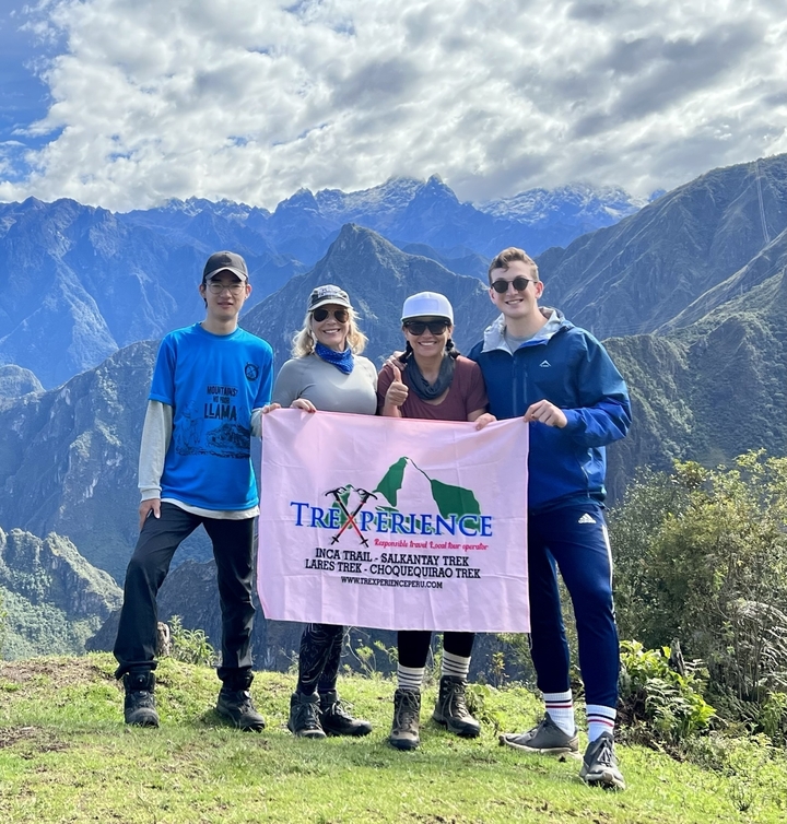 Group holding a banner with a scenic mountain backdrop.