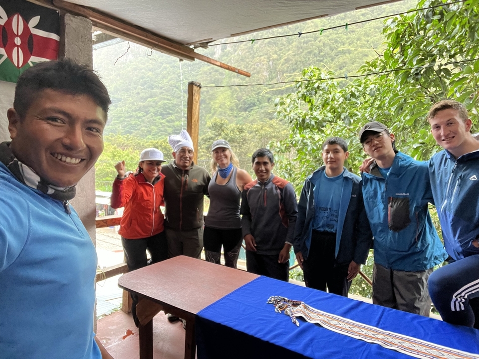 Group of people smiling indoors with lush green trees outside.